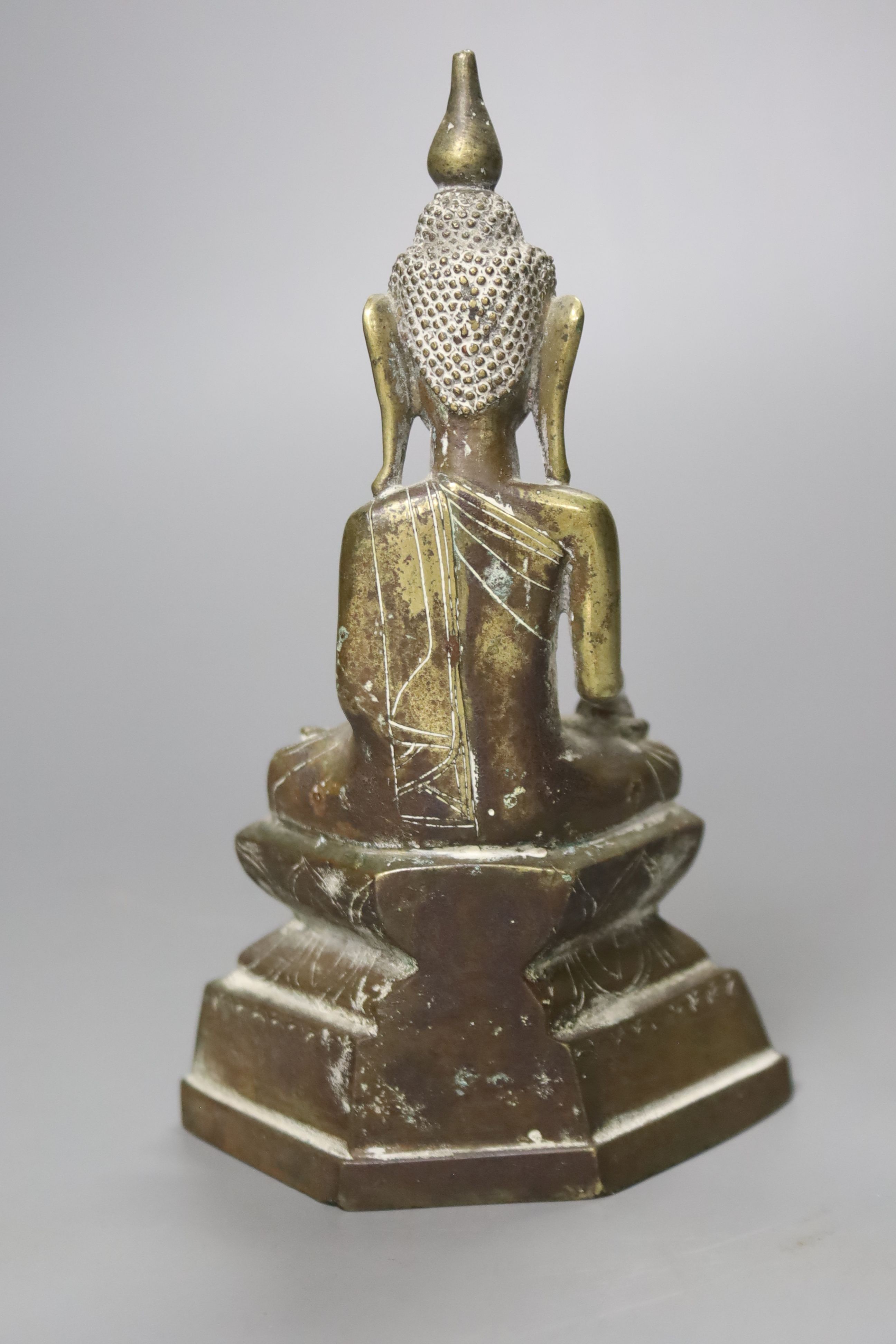 A small 19th century or later Tibetan lacquered cast brass figure of a seated Buddha, (filled), 18cm high